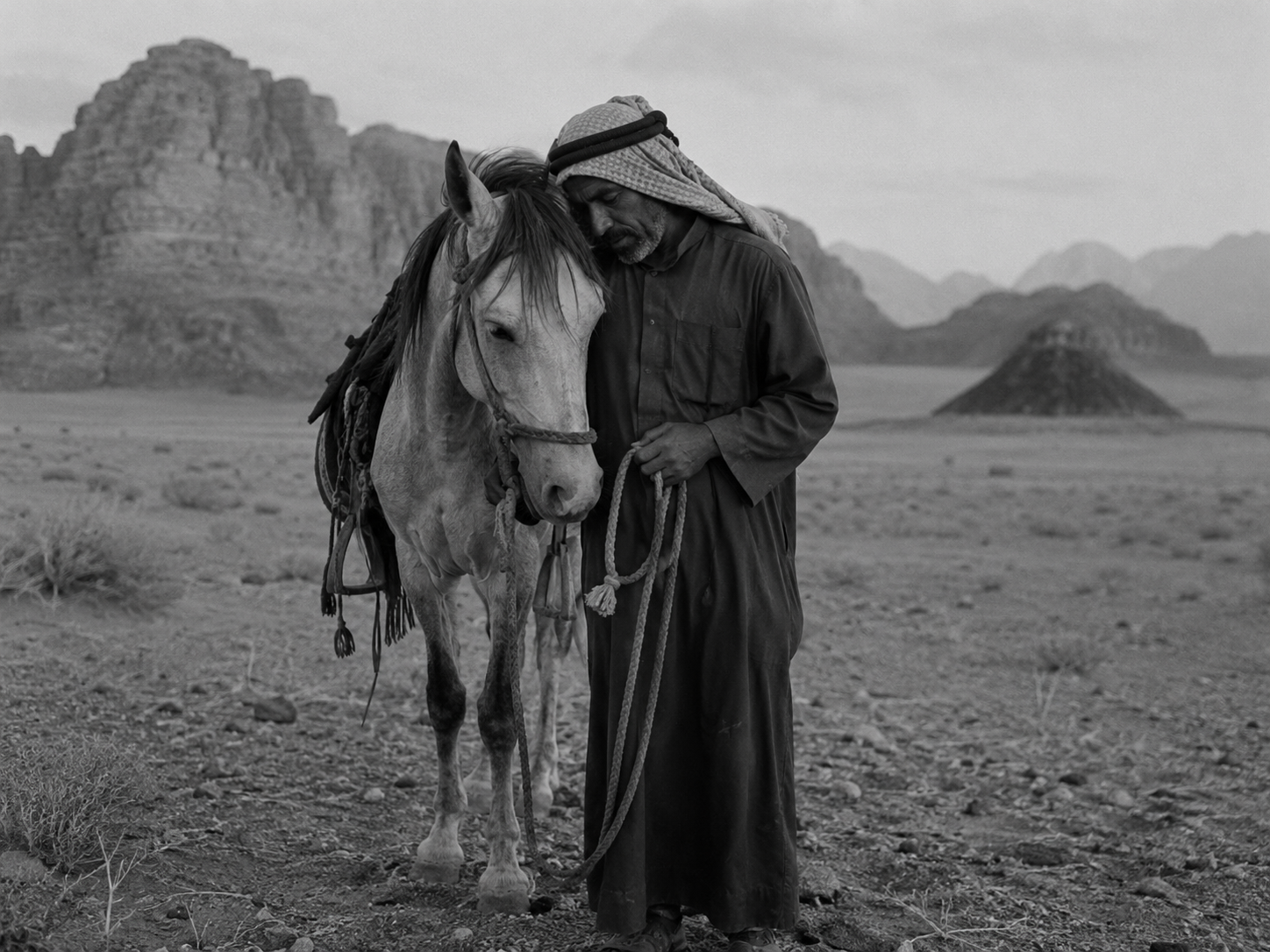 A man sharing a quiet moment with his horse in the desert