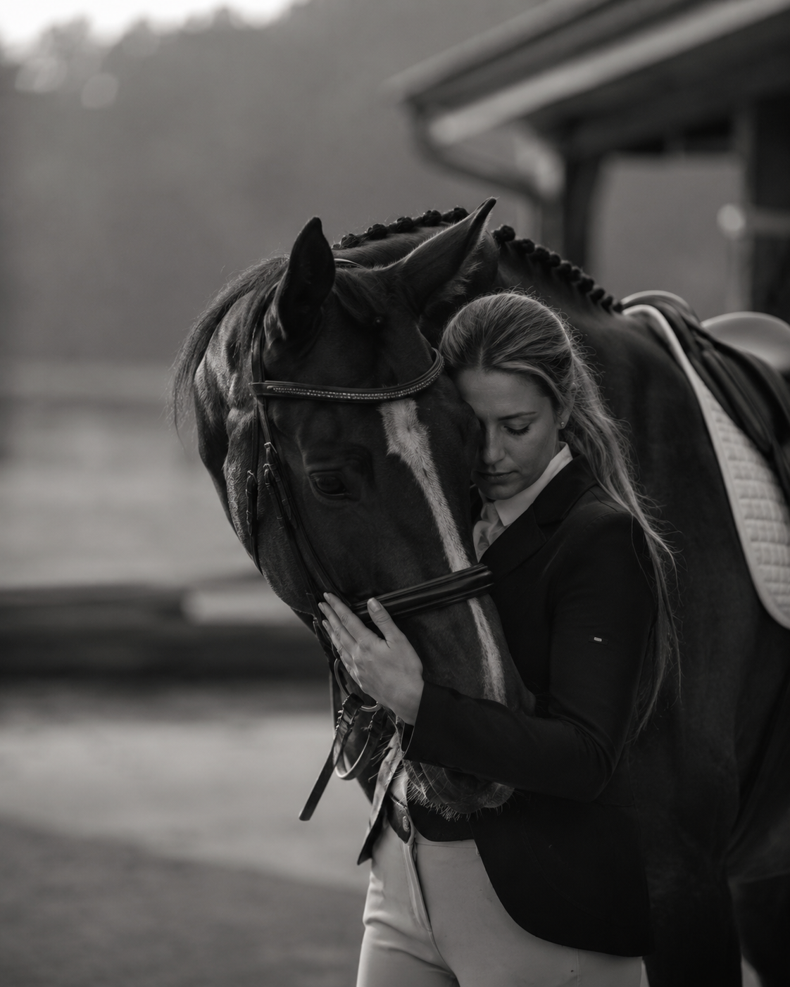 Rider resting her head against her horse in a quiet black-and-white portrait